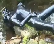 Outdoor walk in the wood and river bath full encased in black latex catsuit and rubber gas mask from girl boys river bath